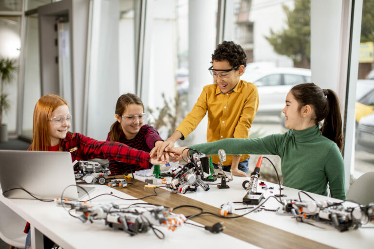 Foto einer Gruppe von Kindern die zusammen mit Klemmbausteinen Roboter bauen